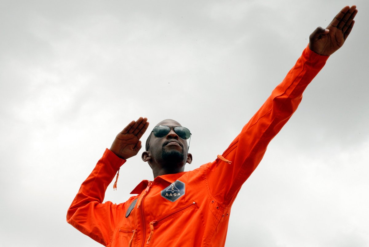 In this picture taken Monday, Feb. 3, 2014, Mandla Maseko, wearing a bright orange Apollo Space Academy jumpsuit demonstrates how a spacecraft blasts off outside his family home at Soshanguve in Pretoria, South Africa. 