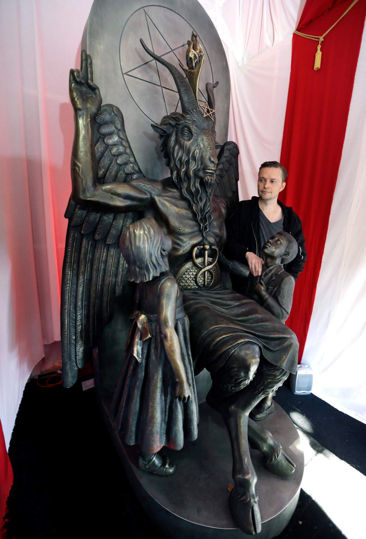 The Satanic Temple founder Lucien Greaves stands next to a statue of the goat-headed idol Baphomet in Salem, Mass.