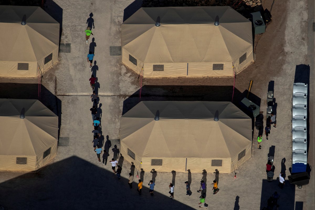 Migrant children are led by staff in single file between tents at a detention facility next to the Mexican border in Tornillo, Texas  June 18, 2018.  