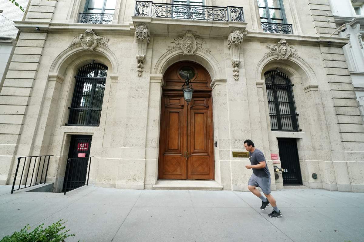 A man runs past the front door of the upper east side home of Jeffrey Epstein, after the Southern District of New York announced charges of sex trafficking of minors and conspiracy to commit sex trafficking of minors, in New York, U.S., July 8, 2019.