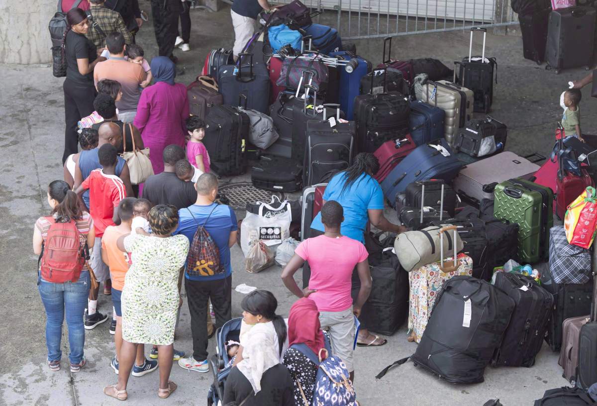 Asylum seekers line up to enter Olympic Stadium, Friday, August 4, 2017 near Montreal. 