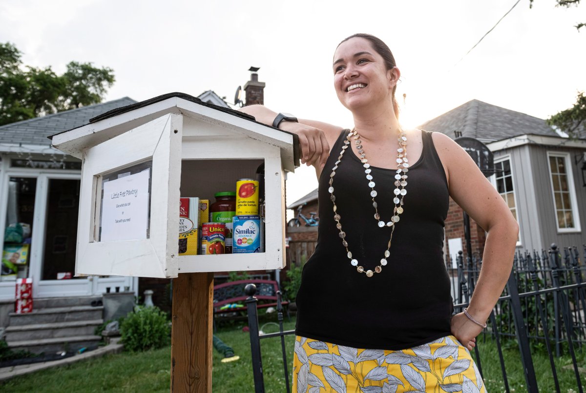 Melissa Rafael poses next to a free food pantry she erected on her property to help ease food insecurity in her neighbourhood, in Toronto, on Friday, July 5, 2019. 