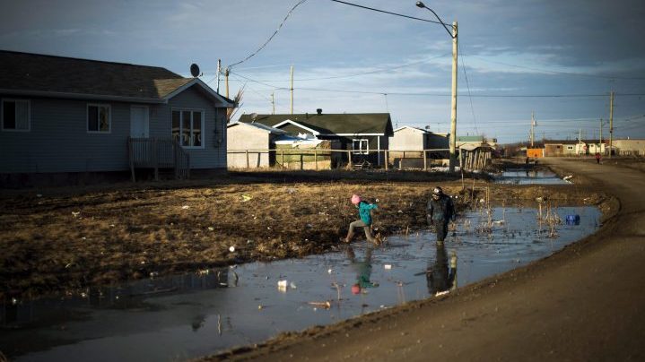 Indigenous children play in water-filled ditches in a northern Ontario First Nations reserve on April 19, 2016. 