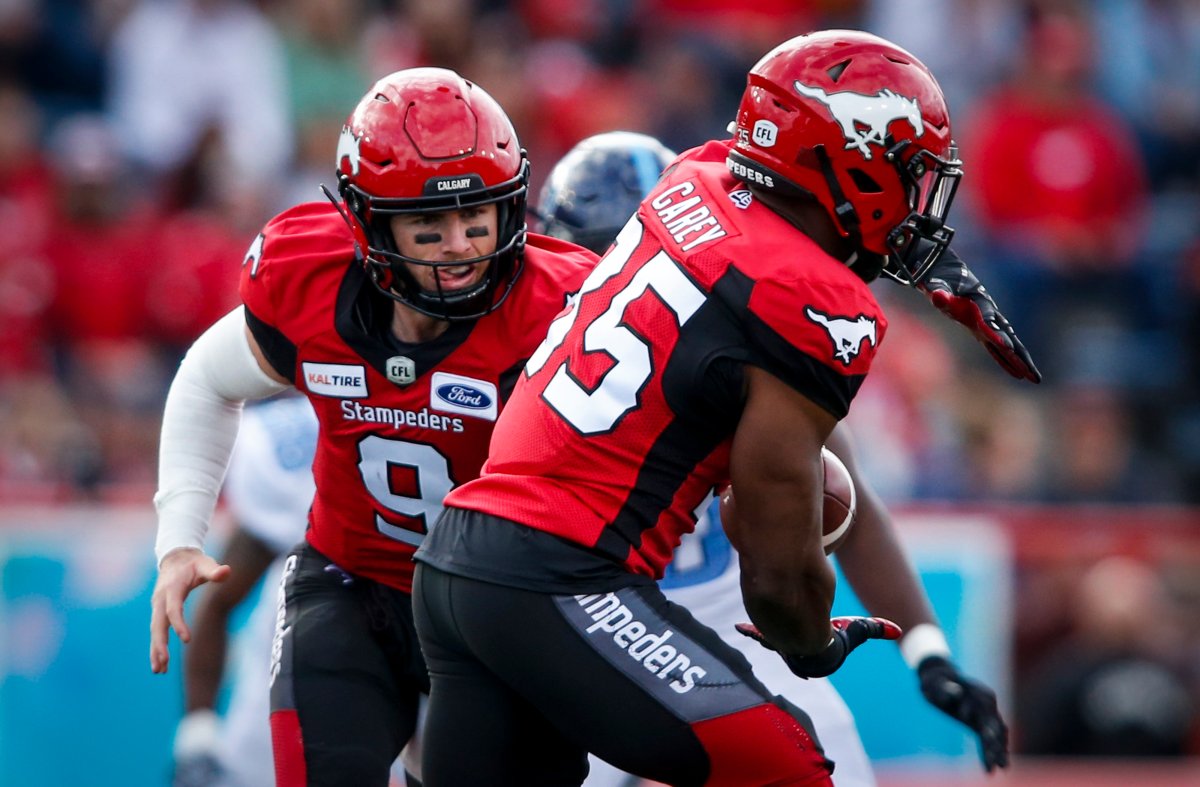 Calgary Stampeders quarterback Nick Arbuckle, left, hands the ball off to Ka'Deem Carey during first half CFL football action against the Toronto Argonauts, in Calgary, Thursday, July 18, 2019. 