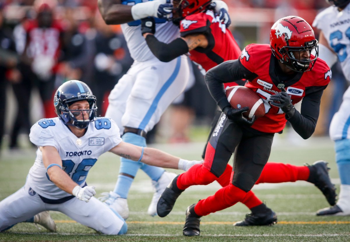Toronto Argonauts' Jimmy Ralph, left, looks on as Calgary Stampeders' Tre Roberson, picks up a fumbled ball and runs it in for a touchdown during second half CFL football action in Calgary, Thursday, July 18, 2019. 