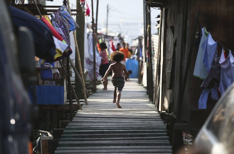 FILE - In this Nov. 15, 2018, file photo, a girl runs towards their home at Port Moresby, Papua New Guinea.