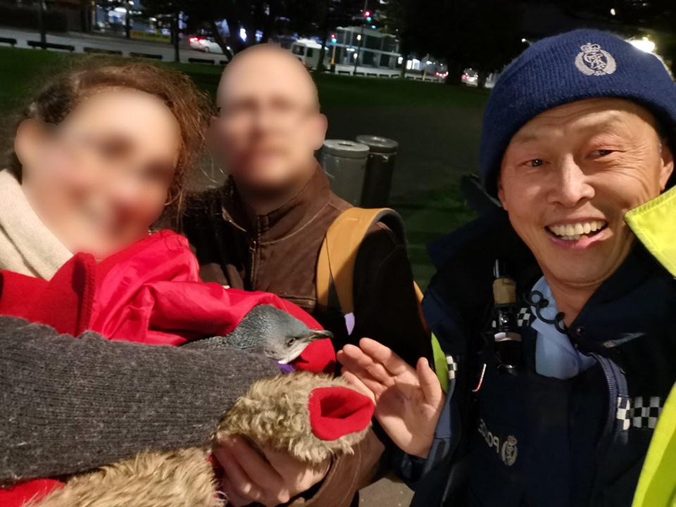 Const. John Zhu of Wellington District Police is shown alongside two citizens who helped capture a blue penguin.