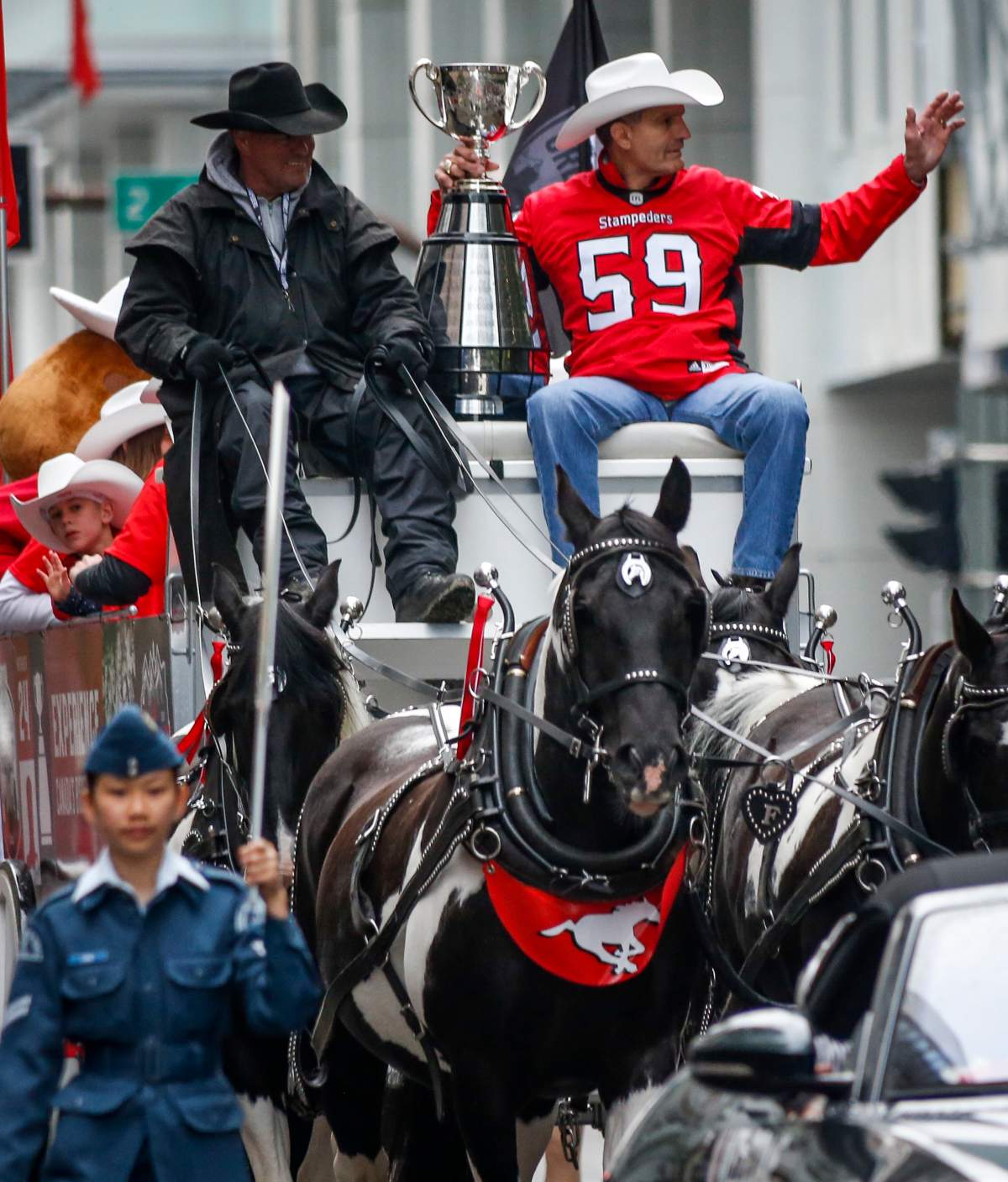 Calgary Stampeder Grey Cup Champion, Rocco Romano, right, waves to the crowds the Grey Cup during the Calgary Stampede parade in Calgary, Friday, July 5, 2019.