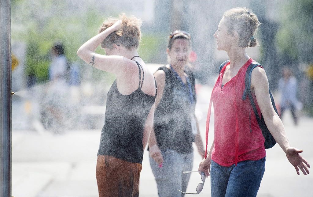 People use misters to cool down during a heat wave in Montreal on July 2, 2018.
