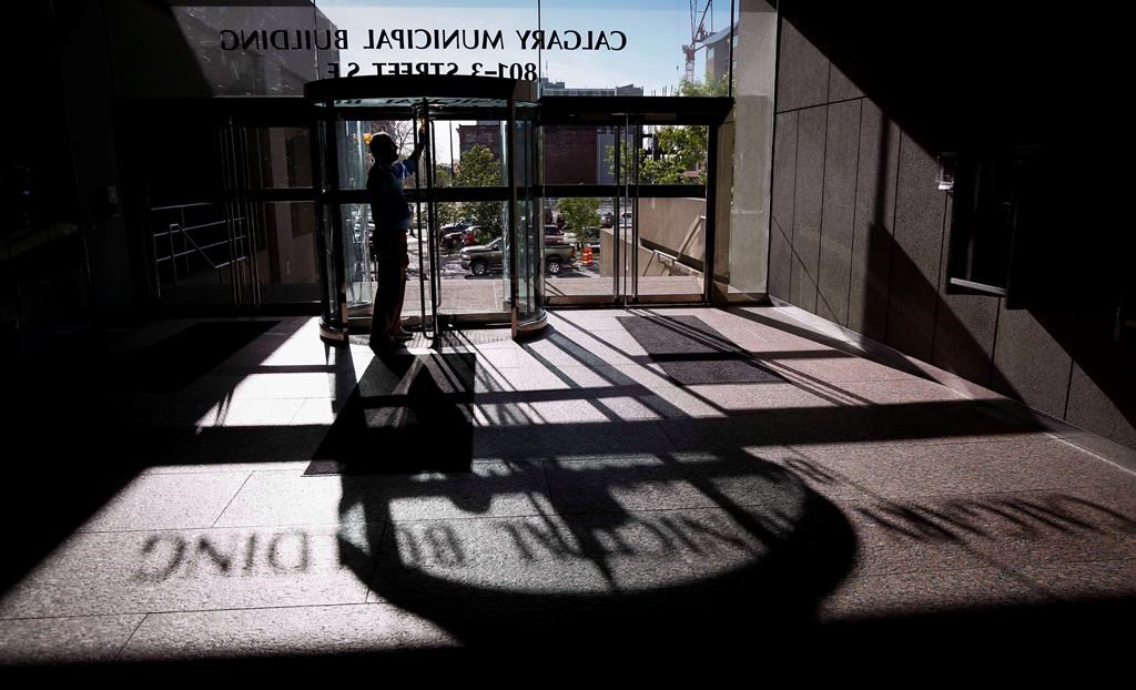 A City of Calgary employee cleans the glass of an entranceway at city hall in Calgary, Alta., on June 20, 2014.