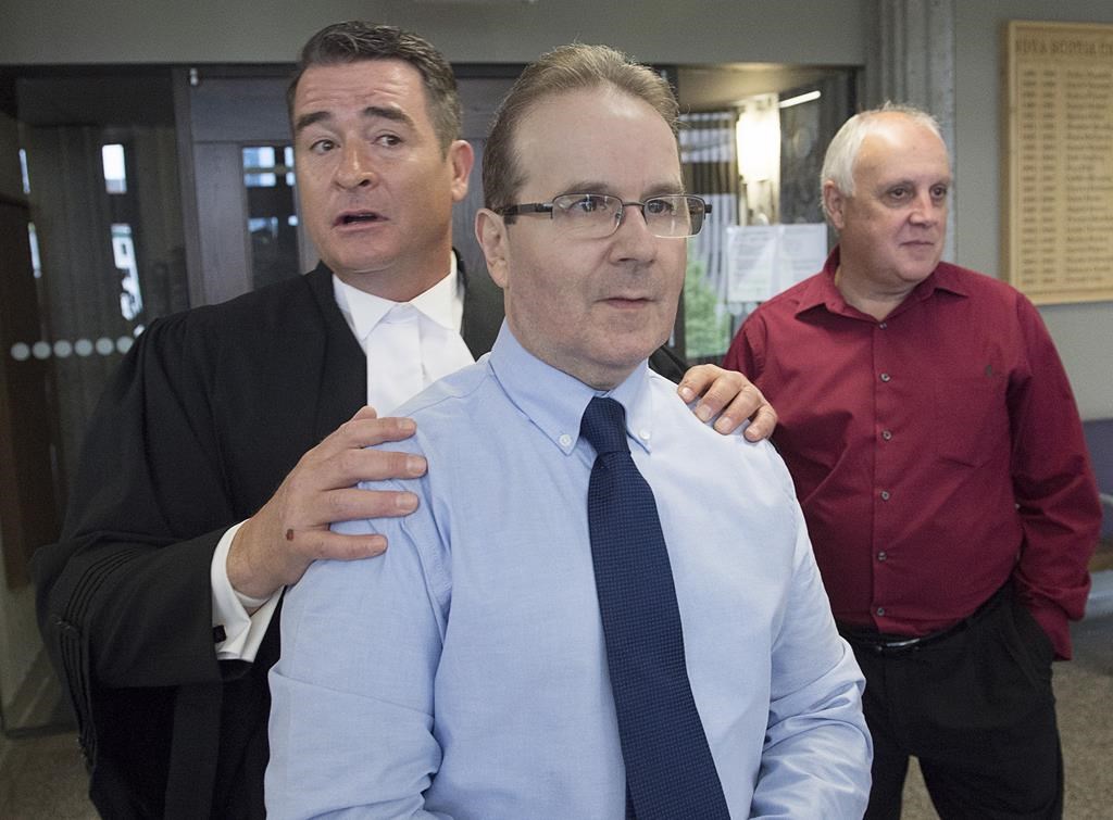 Glen Assoun, the Nova Scotia man who spent almost 17 years in prison for a crime he didn't commit, his lawyer Sean MacDonald and Ron Dalton, right, from the advocacy group Innocence Canada, stand outside Supreme Court in Halifax on Friday, July 12, 2019. Nova Scotia's justice minister says he's waiting for a ruling on whether he has a conflict of interest before commenting on revelations that the RCMP erased evidence in the case of a man wrongfully convicted of murder. THE CANADIAN PRESS/Andrew Vaughan.