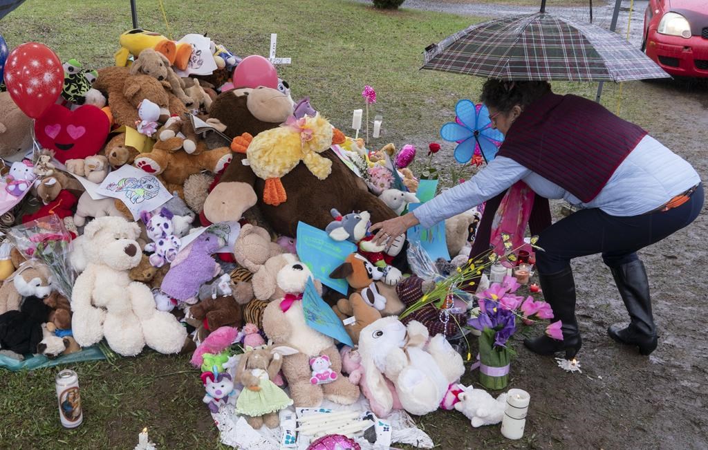 A woman places a stuffed animal in front of the house where lived a 7-year-old girl who was found in critical condition by police on Monday in Granby, Que. on Friday, May 3, 2019. An internal probe has found no one person or service can shoulder the blame for lapses in the case of a slain seven-year-old Quebec girl who'd been followed by youth protection.
