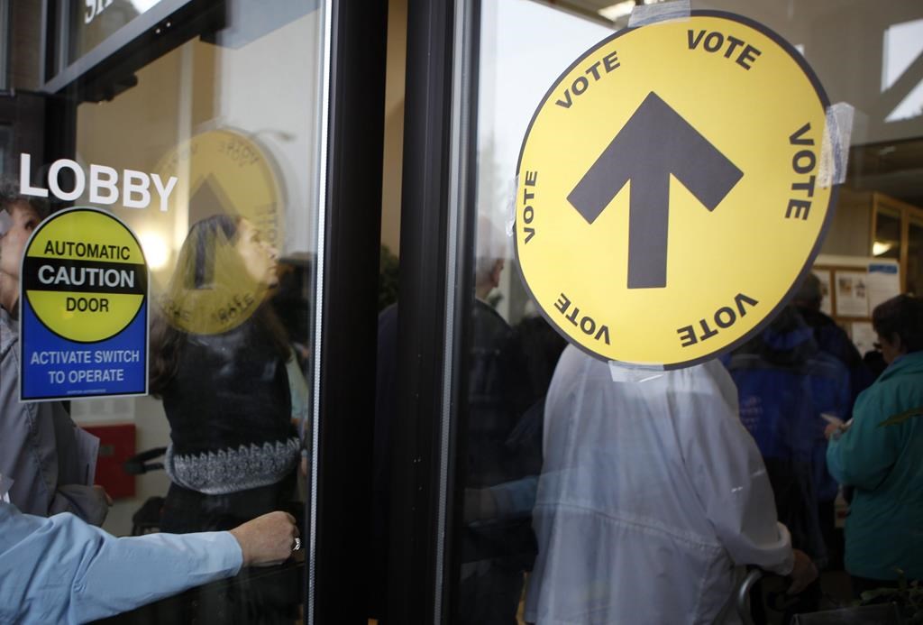 Voters wait in line to cast their ballots both inside and outside the SHOAL Centre on election day in Sidney, B.C., on Oct. 19, 2015.