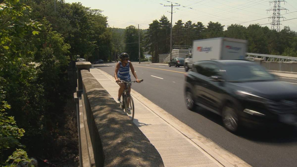 A cyclist pedals along the sidewalk.