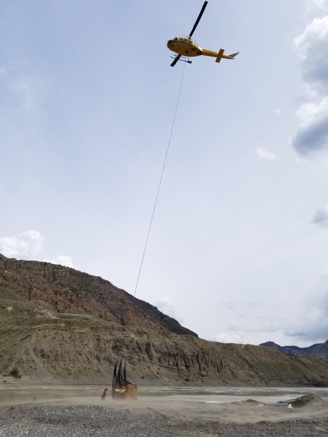 A helicopter transfers a newly-built fish gate to the site of a rock slide on the Fraser River near Big Bar, B.C. on July 19, 2019. The gate will be used to transfer salmon into a holding pond off-channel, where they will be tagged and put into oxygenated tanks. Those tanks will then be taken to a site upstream.