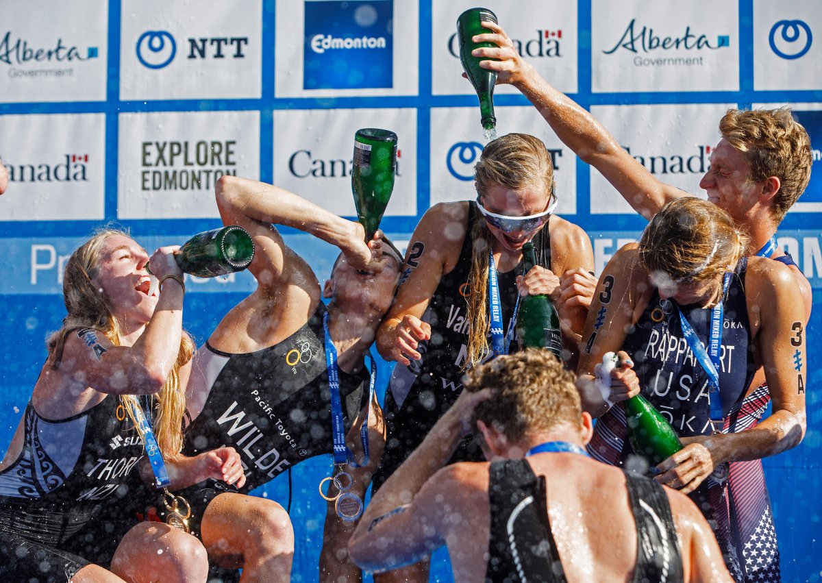 From left, Ainsley Thorpe, Hayden Wilde, Nicole Van Der Kaay and Mathew Hauser of team New Zealand celebrate with champagne as they are joined by the USA's Summer Rappaport and Seth Rider, right, during the Elite Mixed Relay race at the ITU World Triathlon Series in Edmonton on Sunday, July 21, 2019. 
