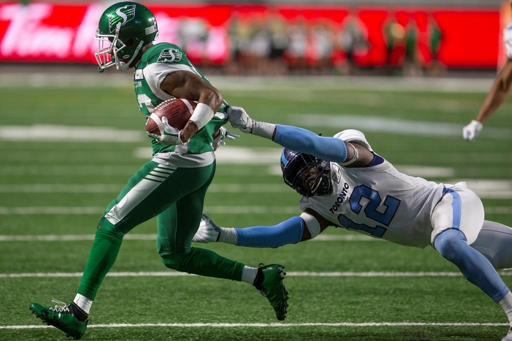 Saskatchewan Roughriders wide receiver Christion Jones (22) runs the ball as Toronto Argonauts linebacker Nelkas Kwemo (12) grabs onto his jersey during second half CFL football action in Regina on Monday, July 1, 2019.