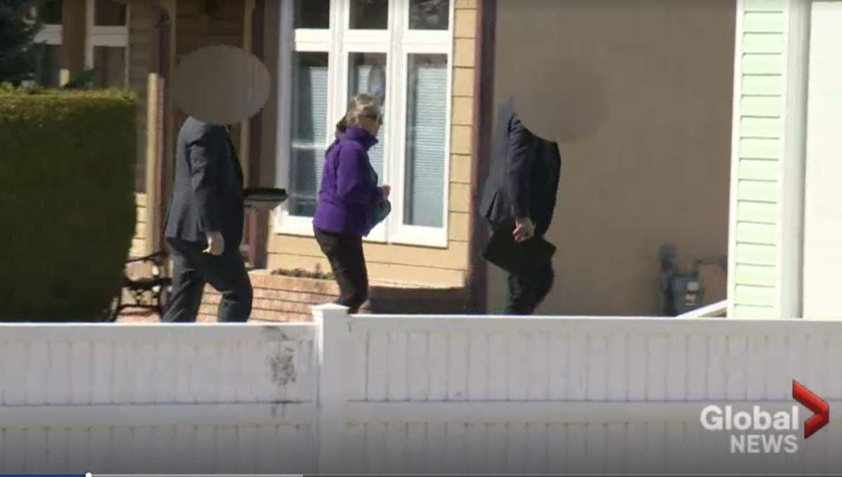 Kathy Brittain escorted into her home by police after her ex-husband allegedly shot and killed four of her neighbours in April. 