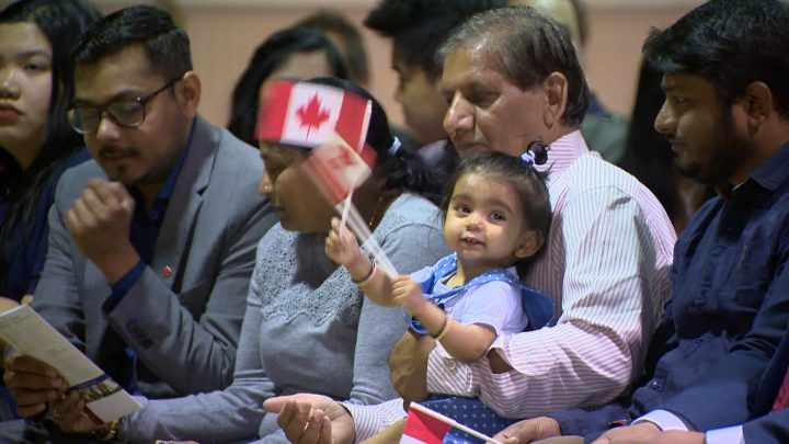 A young girl waves the Canadian flag just before a citizenship ceremony starts in Saskatoon on Monday morning.