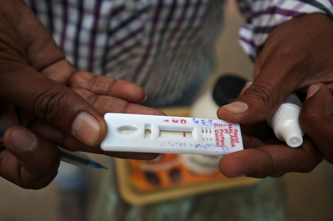 A health worker shows a malaria rapid test kit after collecting blood sample from a resident. Drug-resistant malaria is being found in many parts of Southeast Asia.