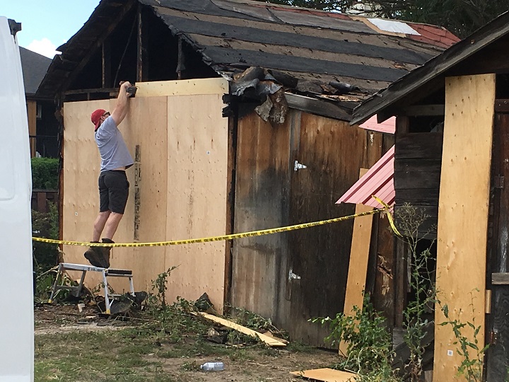 A man boards up a detached garage following a fire inside it on Saturday morning. 