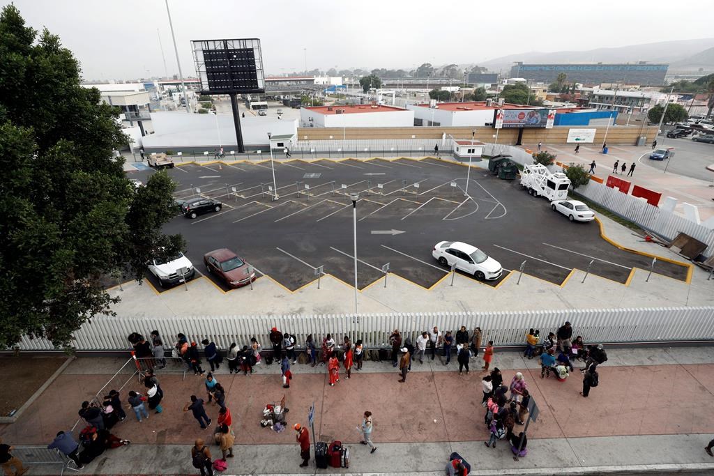 Migrants line up along an entrance to the border crossing as they wait to apply for asylum in the United States, Tuesday, July 16, 2019, in Tijuana, Mexico.