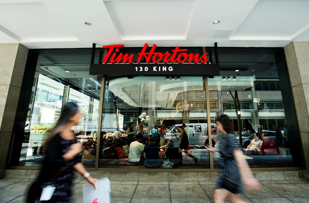 People walk past the newly renovated Tim Hortons in Toronto on Thursday, July 25, 2019. THE CANADIAN PRESS/Nathan Denette.