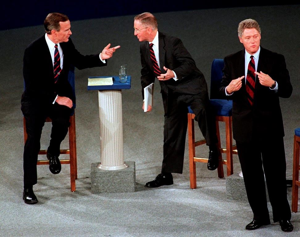 In this Oct. 15, 1992, file photo, President George H.W. Bush, left, talks with independent candidate Ross Perot as Democratic candidate Bill Clinton stands aside at the end of their second presidential debate in Richmond, Va. (AP Photo/Marcy Nighswander, File)