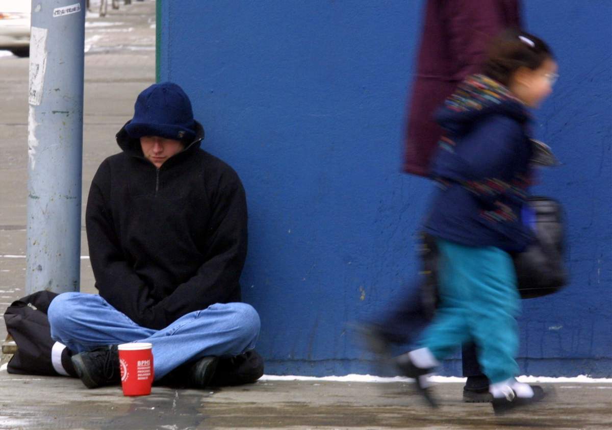 A woman and child pass by a panhandler, Thursday, Mar. 22, 2001. 