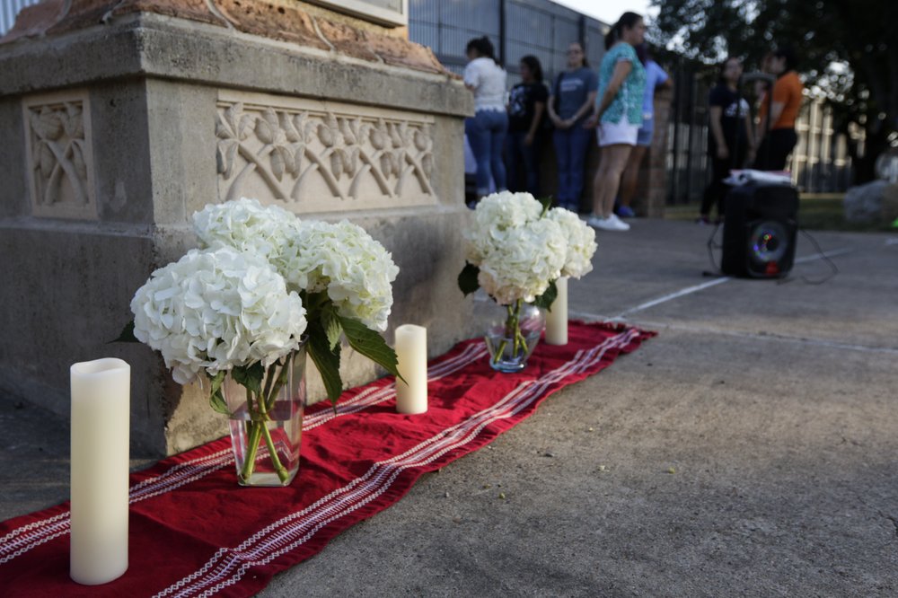 An altar of candles and white hydrangea flowers stands in memoriam of the 22 victims of the recent El Paso shooting during a vigil Sunday, Aug. 11, 2019, at Alice Wilson Hope Park in Brownsville, Texas.