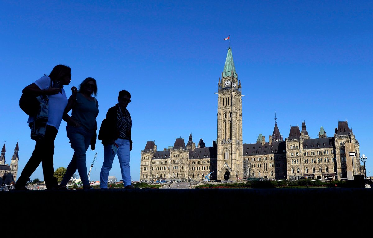 People walk past Parliament Hill in Ottawa on Sunday, Sept. 16, 2018.