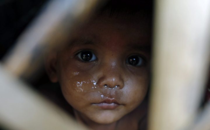 A Rohingya refugee child looks through a window at a makeshift camp in Teknuf in Cox's Bazar.