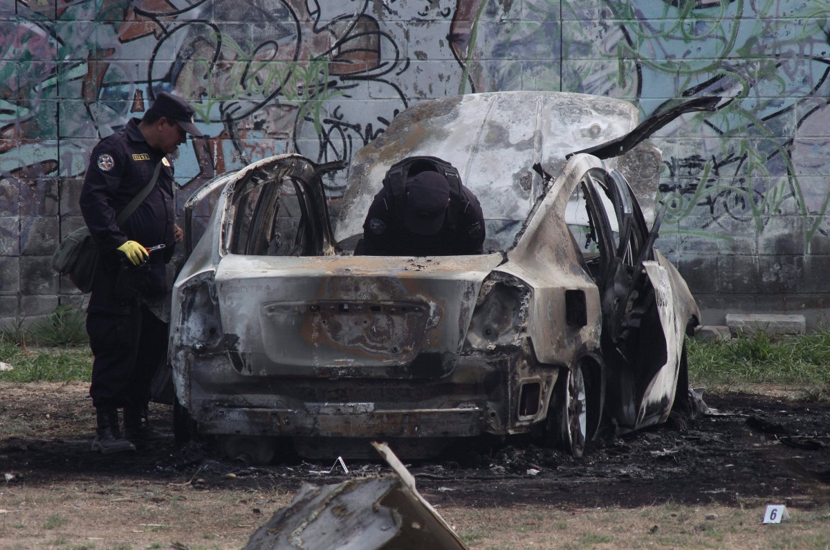Police review the charred remains of a car that exploded as authorities responded to a report of a vehicle with a corpse inside, in the San Bartolo neighborhood of Soyapango, El Salvador, Monday, April 29, 2019. 