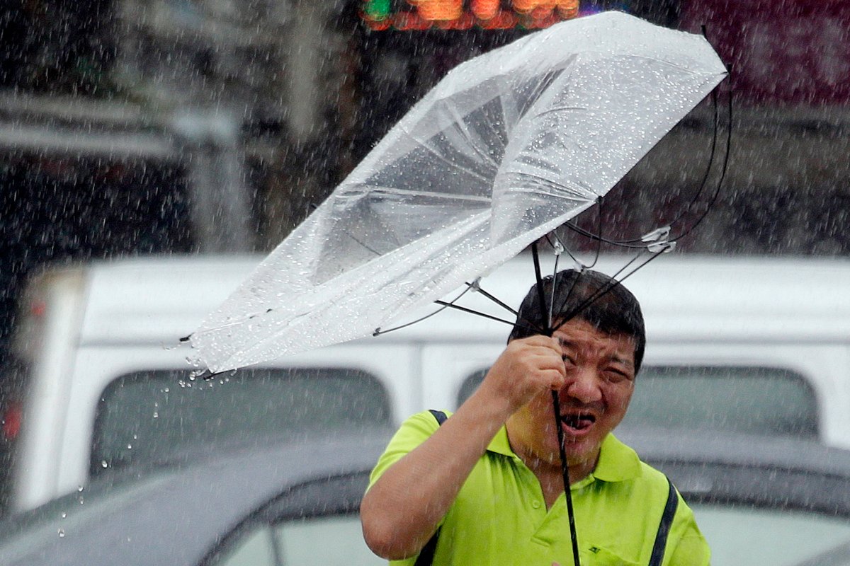 A Taiwanese man holds an umbrella against powerful gusts of wind generated by typhoon Lekima in Taipei, Taiwan, Friday, Aug. 9, 2019. 
