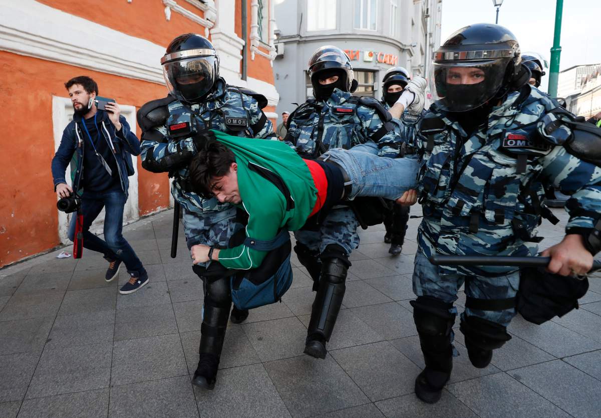 Russian riot policemen carry a detained a participant of an opposition rally who decided to continue their protest in front of presidential administration building in the center of Moscow, Russia, Aug. 10, 2019. 