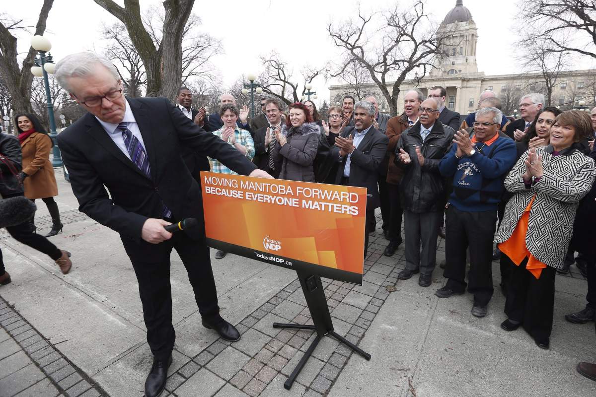 Manitoba Premier and NDP Leader Greg Selinger checks his sign before speaking to media after asking the Lieutenant Governor of Manitoba to call the 2016 provincial election. The slogan on the party’s podium is now being used by the Progressive Conservatives.