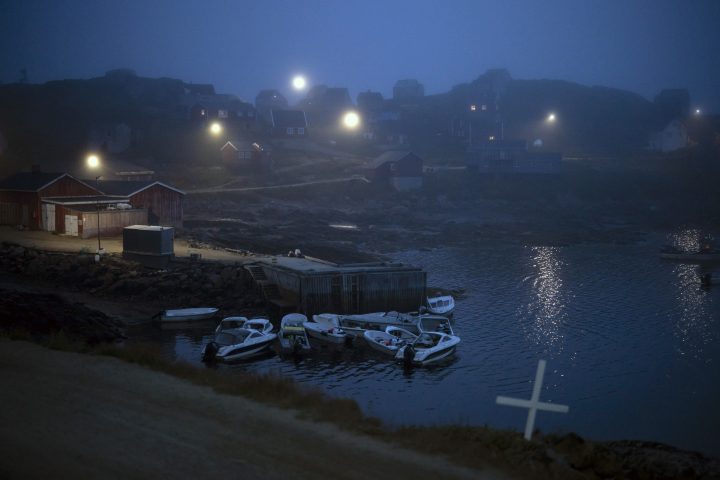 A cross sits on the side of the road as fog covers homes in Kulusuk, Greenland, early Thursday, Aug. 15, 2019.
