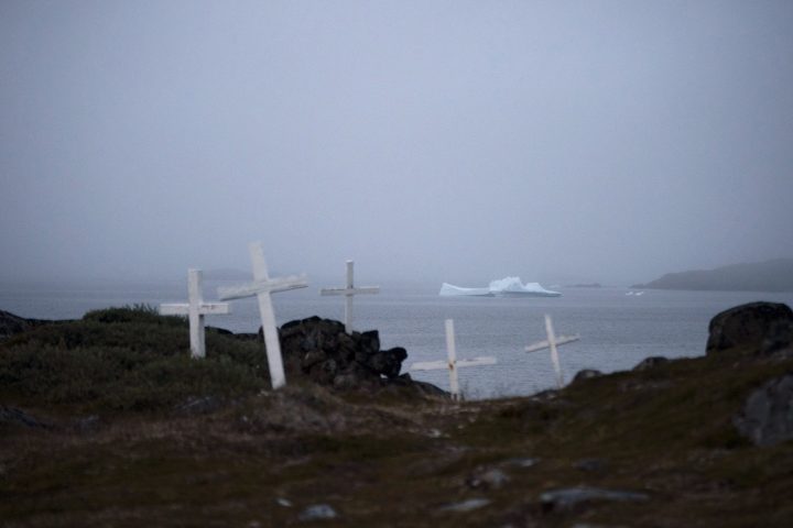 An iceberg floats near a cemetery in Kulusuk, Greenland, early Thursday, Aug. 15, 2019.