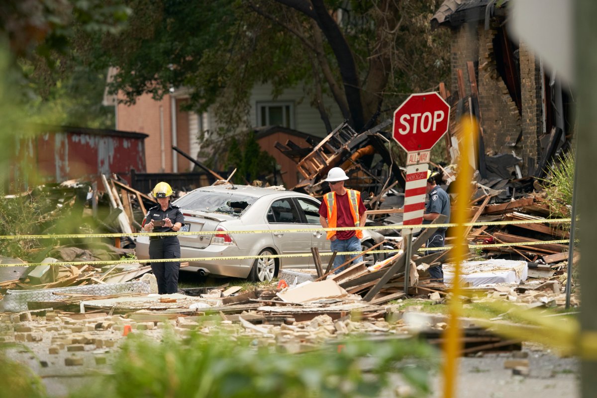 Fire officials investigate the scene of a house explosion caused by a car crashing into a house in London, Ont., Thursday, August 15, 2019.