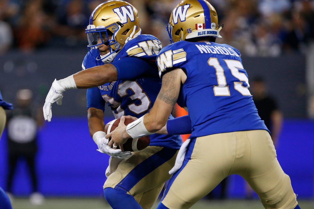 Winnipeg Blue Bombers quarterback Matt Nichols (15) hands off to Andrew Harris (33) against BC Lions during the second half of CFL action in Winnipeg Thursday, August 15, 2019.