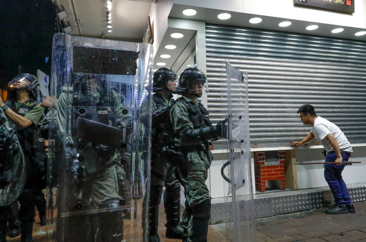Police officers armed with riot gears stand guard as a shopkeeper shuts a door during pro-democracy protesters' march in Hong Kong Saturday, Aug. 17, 2019. Another weekend of protests is underway in Hong Kong as Mainland Chinese police are holding drills in nearby Shenzhen, prompting speculation they could be sent in to suppress the protests. 