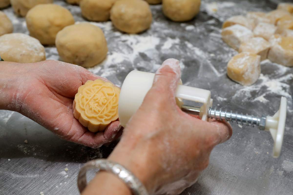 In this Aug. 9, 2019 photo, a staff member stamps the Chinese words “Hong Kong people” on the mooncake at Wah Yee Tang bakery in Hong Kong. (AP Photo/Kin Cheung)