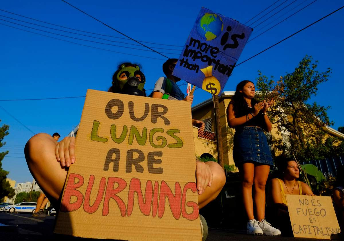 Protesters with banners block the road outside of the Brazilian Embassy during a protest in Nicosia, Cyprus, Friday, Aug. 23, 2019. (AP Photo/Petros Karadjias)