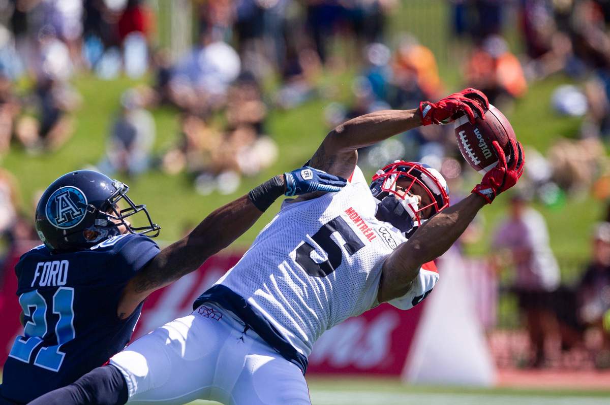 DeVier Posey with Montreal makes a catch as Quadarius Ford with Toronto tries to block the ball during second quater CFL action in Moncton on Sunday, August 25, 2019.