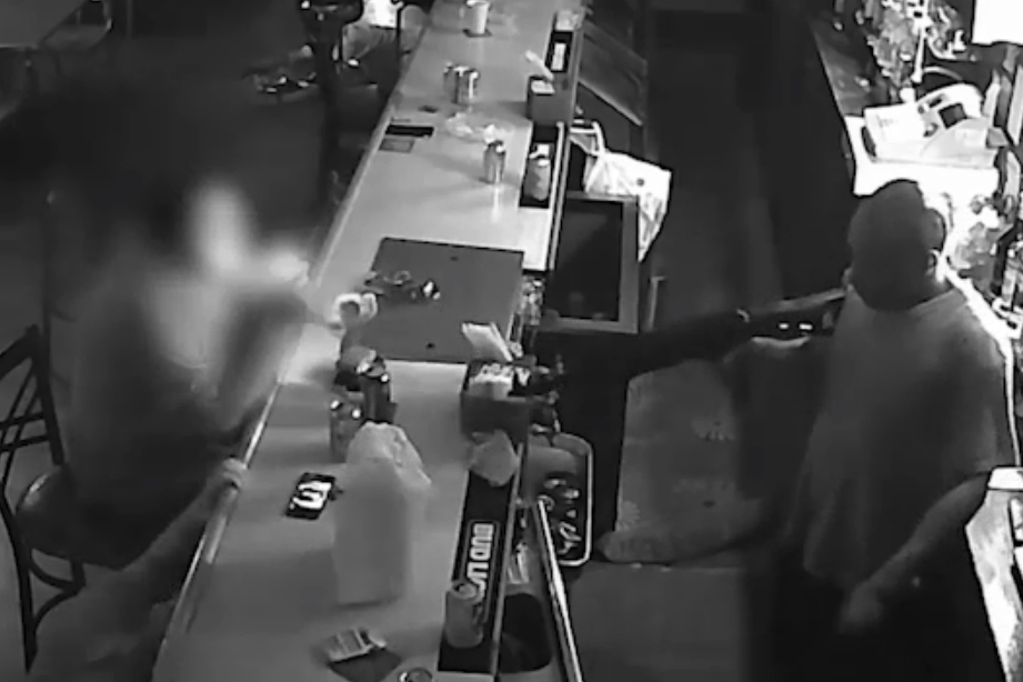 A robbery suspect, right, points his gun at a bar patron who is lighting a cigarette during an attempted robbery at Behrmann’s Tavern in St. Louis, Mis., in this image from video on Aug. 28, 2019.