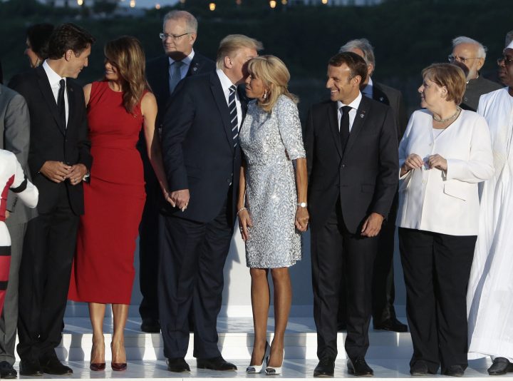 U.S. President Donald Trump kisses Brigitte Macron on the cheek, centre, while Prime Minister Justin Trudeau speaks to Melania Trump, left, and French President Emmanuel Macron and German Chancellor Angela Merkel look on, right, at the G7 summit in Biarritz, France, Aug. 25, 2019.