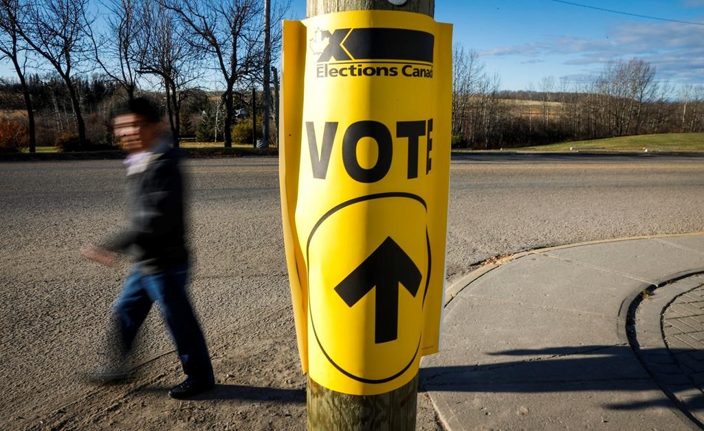 Canadians will be asked this fall to choose between moving forward with the Liberals or getting ahead with the Conservatives. A voter walks past a sign directing voters to a polling station for the Canadian federal election in Cremona, Alta., Monday, Oct. 19, 2015.