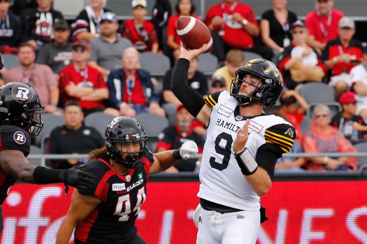 Hamilton Tiger-Cats quarterback Dane Evans (9) throws the ball as he is chased by Ottawa Redblacks J.R. Tavai (44) during second quarter CFL action in Ottawa on Saturday, August 17, 2019.