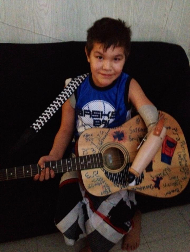 A photo of Dillon as a child holding a guitar.