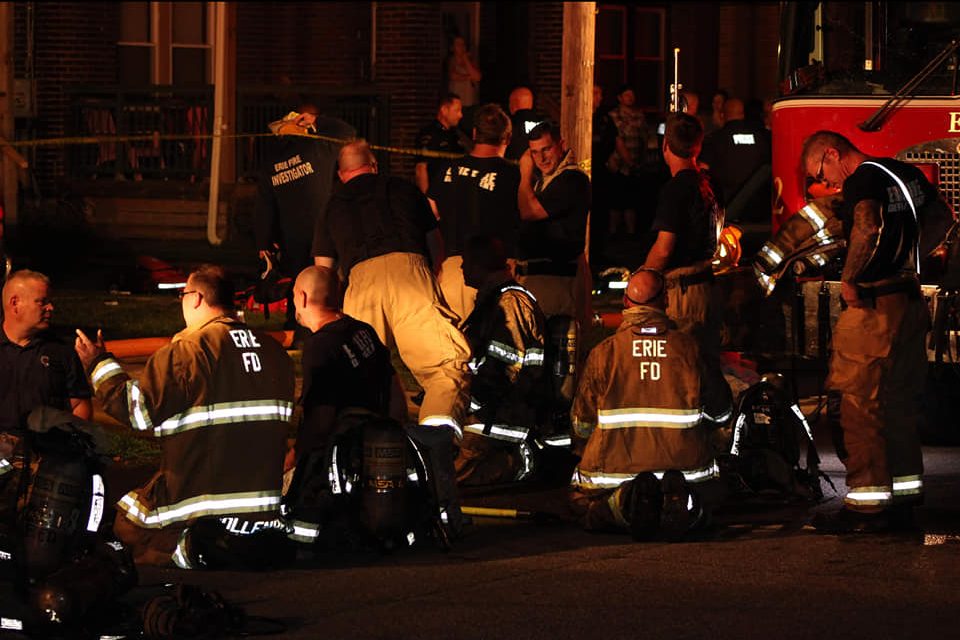 Firefighters in Erie, Penn., kneel in grief outside a home daycare where five children died in a blaze on Aug. 11, 2019.